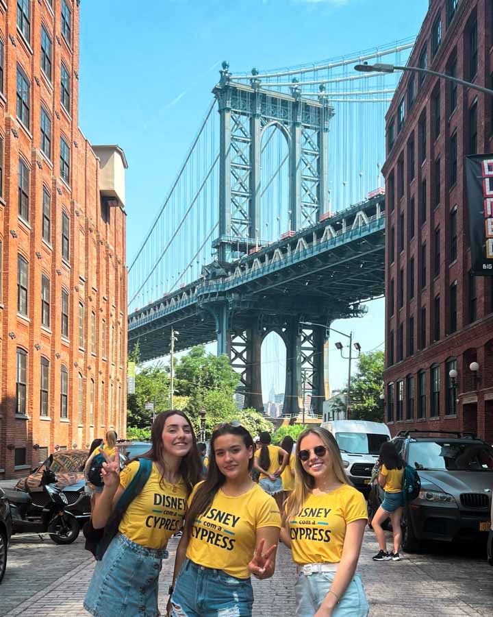 Três passageiras no DUMBO com a Manhattan Bridge ao fundo